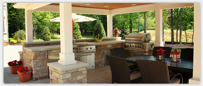 Outdoor kitchen installed by Exscape Designs with a grill and storage in a stone island