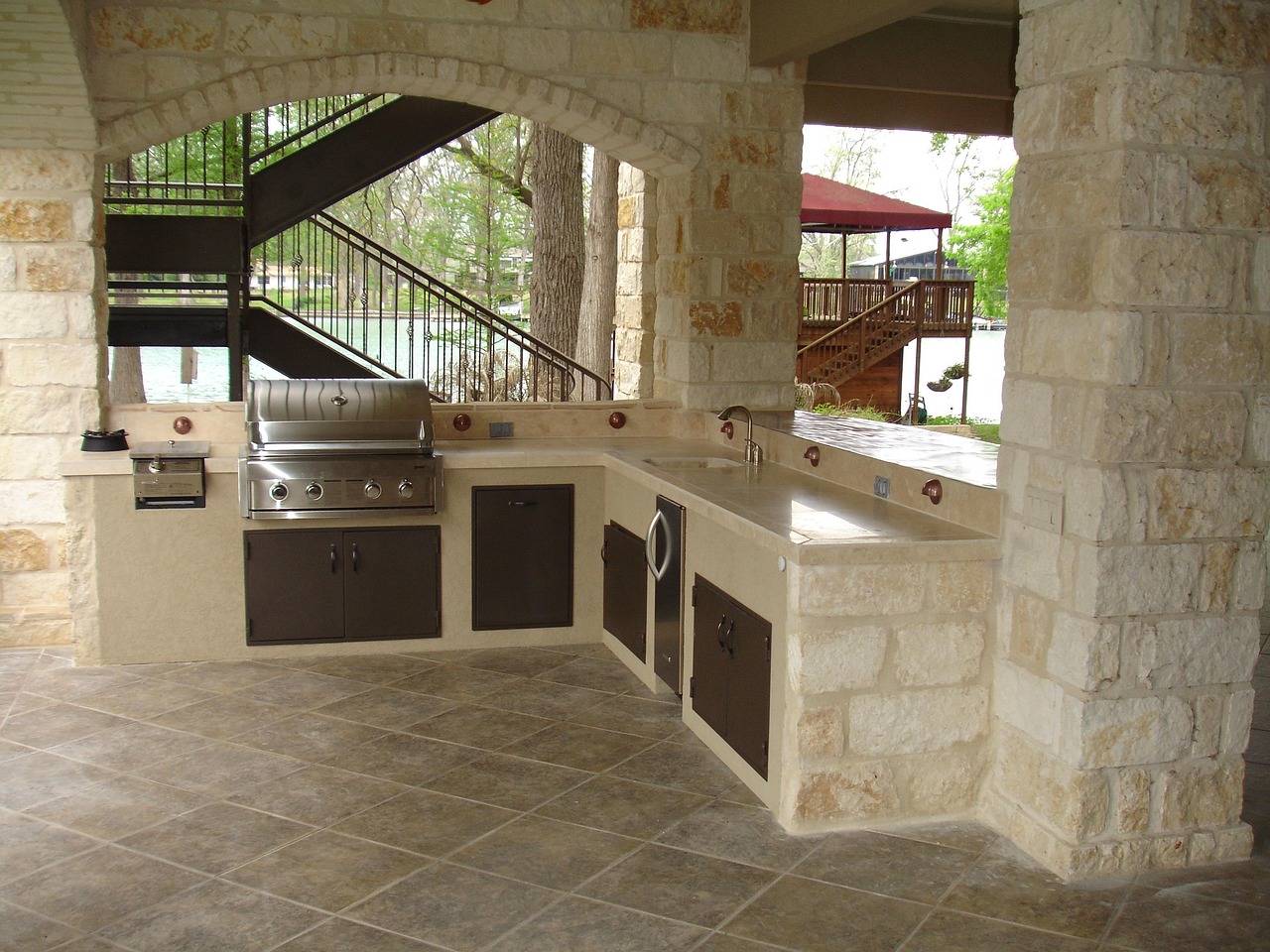 Stone outdoor kitchen with a built-in grill, sink, and storage